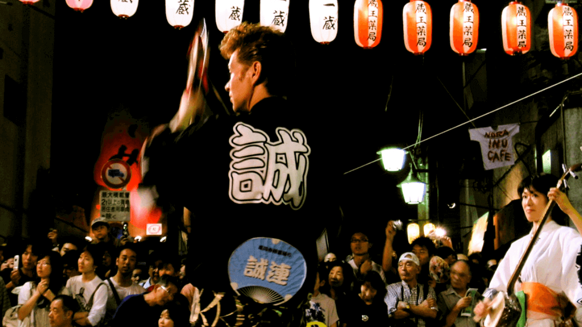 一名日本表演者在日本东京高音寺的Awa Odori音乐节上与粉丝共舞。